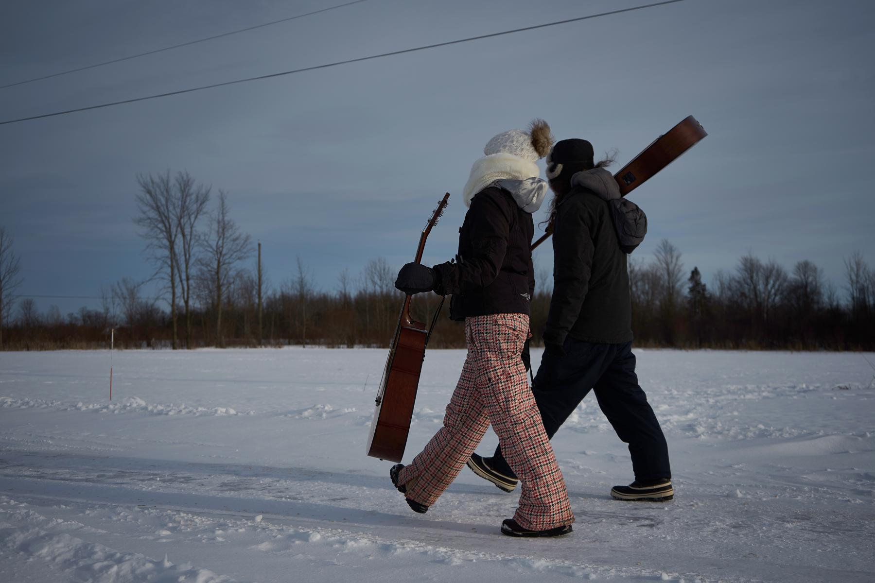 Jenn and Matt walking in snowy field with instruments