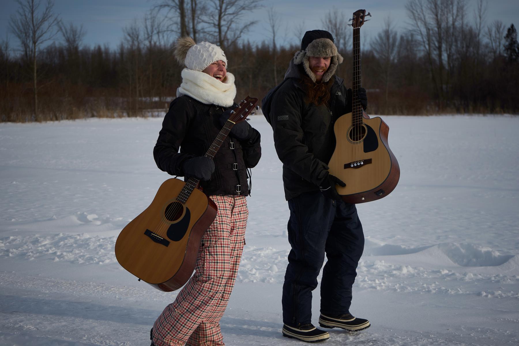Jenn and Matt posing in snowy field with instruments