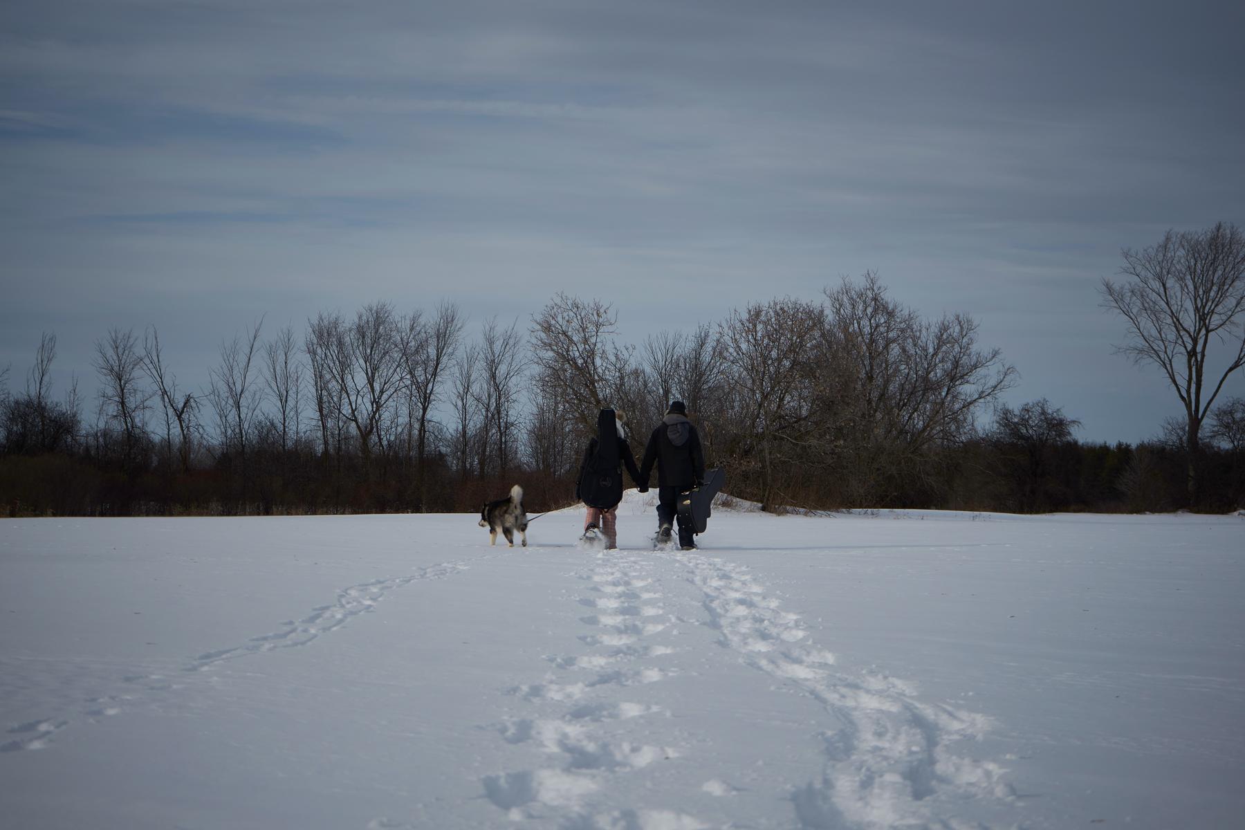 Jenn Matt and Shadow walking off in a snowy field